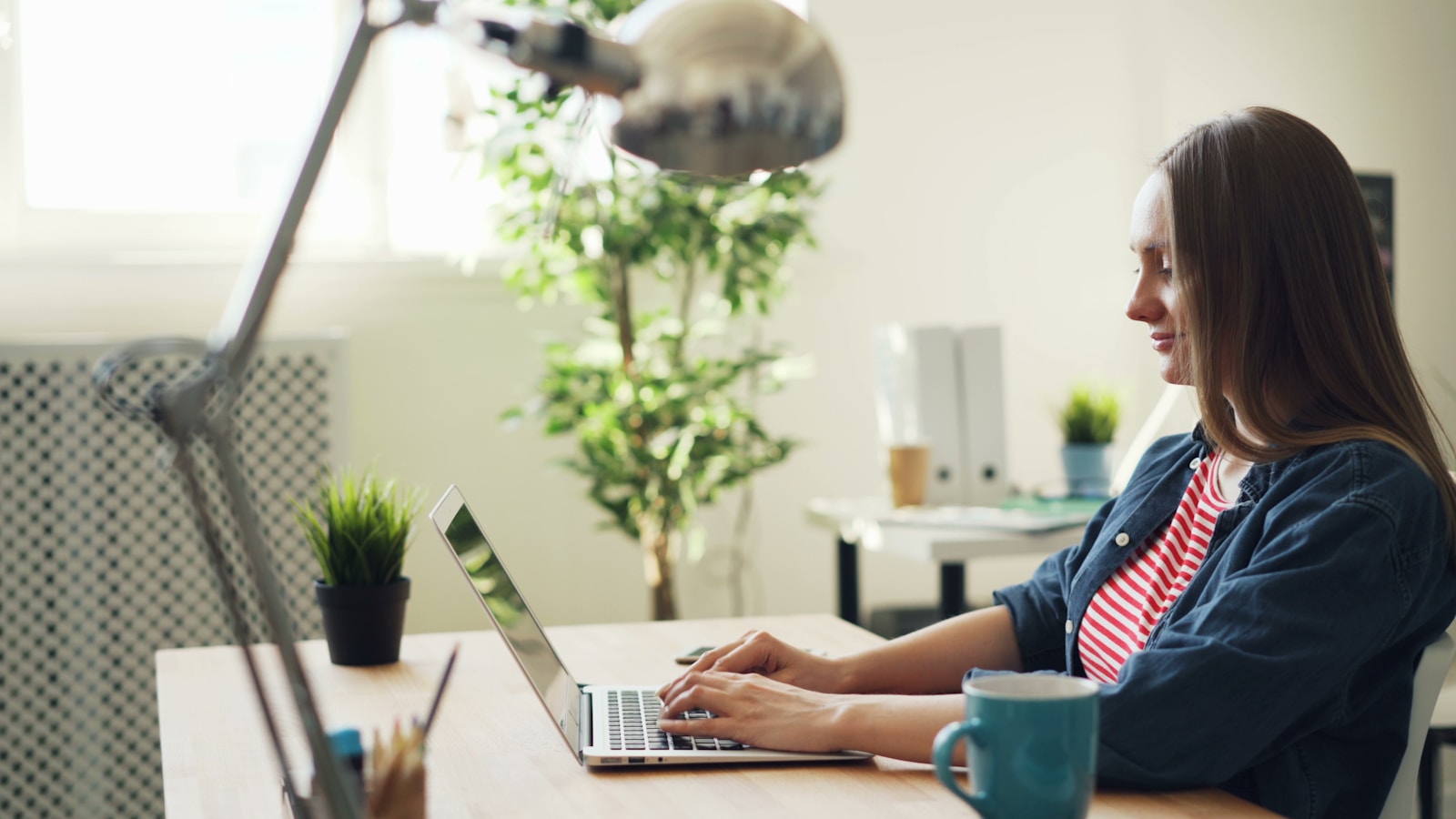 Woman smiling while using a laptop at her desk